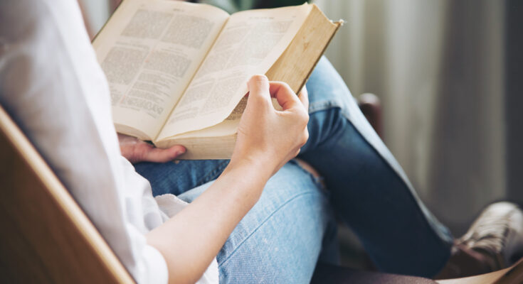 A imagem é a foto de uma mulher lendo um livro.