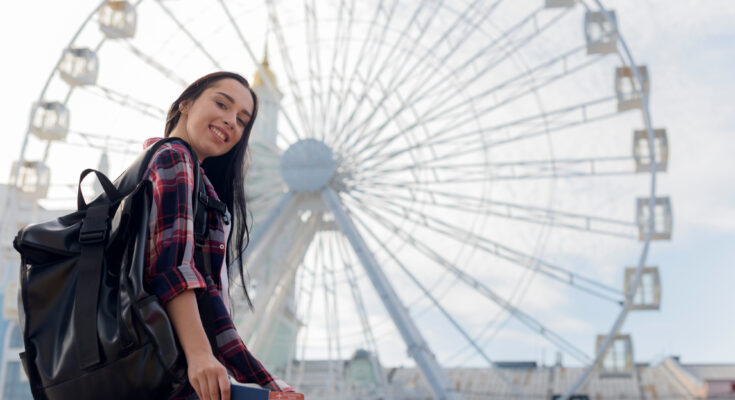 A imagem é a foto de uma jovem estudante defronte a London Eye.