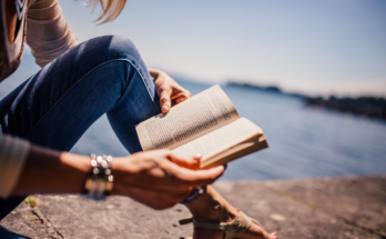 A imagem é a foto de uma mulher lendo um livro.