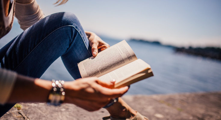 A imagem é a foto de uma mulher lendo um livro.