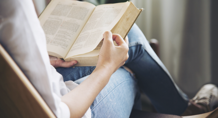 A imagem é a foto de uma mulher lendo um livro.